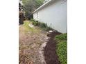 Narrow side yard with mulch, vegetation, and an external wall at 417 Victoria Hills Dr, Deland, FL 32724