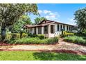 A lovely property framed by a brick walkway and lush landscaping, leading to a charming facade with inviting porch at 5549 Aragon Ave, De Leon Springs, FL 32130