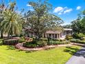 Charming home surrounded by manicured landscaping, brick walkways, mature trees, and lush green lawn for a welcoming appeal at 5549 Aragon Ave, De Leon Springs, FL 32130
