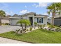 Inviting single-story home with a three-car garage, lush lawn, beautiful landscaping, and decorative shutters at 660 Mosaic Blvd, Daytona Beach, FL 32124