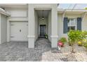 Covered front entrance with stone pavers, decorative light fixture, and view of the three-car garage at 660 Mosaic Blvd, Daytona Beach, FL 32124