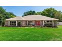 Charming single-story brick home with a well-manicured lawn and a vibrant red front door, creating an inviting first impression at 68 Spring Lake Dr, Debary, FL 32713