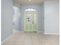 Bright foyer with tile flooring, showcasing an arched doorway and a decorative glass front door at 8231 Sw 79Th Ct, Ocala, FL 34476