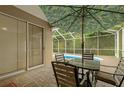 Outdoor patio with table and chairs, shaded by an umbrella, adjacent to the screened-in pool area at 8231 Sw 79Th Ct, Ocala, FL 34476