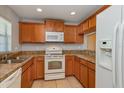 Well-lit kitchen features tile floors, warm wood cabinets, and modern white appliances at 109 Bel Fiore Cv, Sanford, FL 32773