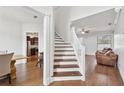 Bright foyer with hardwood floors leading to a staircase, living room, and glimpses of a modern kitchen at 1491 Nappa Dr, Port Orange, FL 32128