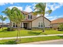 Beautifully landscaped two-story home featuring a tile roof, green lawn, and mature palm trees at 163 Rosa Bella Vw, Debary, FL 32713