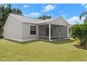 A view of the back exterior with a well-maintained lawn and screened-in patio at 1930 Harston Trl, The Villages, FL 32162