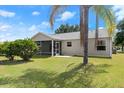 A view of the back exterior showcasing a large yard and screened patio at 1930 Harston Trl, The Villages, FL 32162