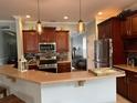 Open kitchen with granite countertops, stainless steel appliances, dark wood cabinets, and decorative pendant lighting at 201 Asterbrooke Dr, Deland, FL 32724