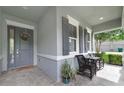 Welcoming front porch with gray door, matching shutters, and cozy seating area at 220 Asterbrooke Dr, Deland, FL 32724