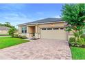 Charming home exterior showcases a brick driveway, lush lawn, and well-maintained landscaping at 2406 Kennington Cv, Deland, FL 32724