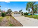 Home with an attached two-car garage and long driveway, featuring a manicured lawn and mature palms at 2526 Chester Ave, New Smyrna Beach, FL 32168