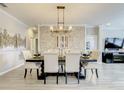 Elegant dining room with a decorative stone wall, modern chandelier, and a large table with white chairs at 260 Teddy Rushing St, Debary, FL 32713