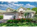 Charming home showcasing lush landscaping, a green tile roof, and a pristine white two-car garage at 470 Foxhill Dr, Debary, FL 32713