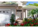 Inviting front entrance with a decorative white door, lush red flowers, and a well-maintained two-car garage at 470 Foxhill Dr, Debary, FL 32713