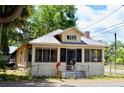 View of a quaint bungalow with a screened porch, metal roof, and a fenced yard on a sunny day at 580 Ronnoc Ln, New Smyrna Beach, FL 32168