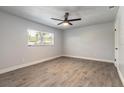 Bright bedroom with wood-look tile floors, neutral walls, ceiling fan, and natural light at 612 Moonpenny Cir, Port Orange, FL 32127
