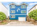 Charming three-story blue home with a dolphin design, white trim, and a white garage door at 6847 S Atlantic Ave, New Smyrna Beach, FL 32169
