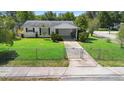A charming home features a vibrant green lawn, complemented by a chain-link fence at 708 Wayne Ave, New Smyrna Beach, FL 32168