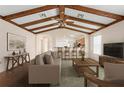 Spacious, staged living room featuring wood beam ceiling, ceiling fan, and view to kitchen at 11094 Se 173Rd Ln, Summerfield, FL 34491