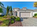 Charming home showcasing a manicured lawn, paver driveway, and attached two car garage at 133 Azure Mist Way, Daytona Beach, FL 32124