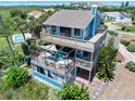 Exterior of a multi-level home with a large deck and screened-in area with outdoor seating at 14 Marsh Ct, Ponce Inlet, FL 32127