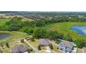 An aerial view shows a private home surrounded by lush greenery, neighboring houses, and tranquil ponds at 1480 Leitrim Loop, Apopka, FL 32703