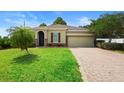 Charming home featuring a brick driveway, two car garage, a well-manicured lawn and shuttered windows at 1480 Leitrim Loop, Apopka, FL 32703