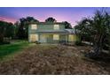 Charming two-story home with a covered front porch, surrounded by lush trees under a colorful dusk sky at 1560 7Th Ave, Deland, FL 32724