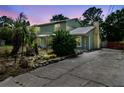 Two-story home with a yellow and green exterior, a metal roof, a brick trim, and a concrete driveway at 1560 7Th Ave, Deland, FL 32724