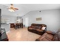 Cozy living room featuring tile floors, a ceiling fan, a dining area, and a comfortable leather sofa at 2416 Candlewick St, Deltona, FL 32738