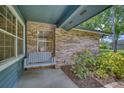 Cozy front porch featuring a charming swing, brick accents, and lush landscaping at 2551 Cross Country Dr, Port Orange, FL 32128