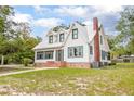 Beautiful two-story home featuring a white exterior, metal roof, brick foundation, and verdant window trim at 257 Huntington Dr, Deland, FL 32724