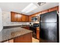 Compact kitchen featuring granite countertops, wooden cabinets, and modern appliances at 3023 S Atlantic Ave # 4020, Daytona Beach, FL 32118