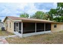 A screened in back porch with a tan facade and a concrete tile patio at 522 Grace Ave, Deland, FL 32724