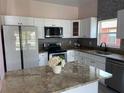 Modern kitchen featuring white cabinets, granite countertops, and stainless steel appliances at 707 Hamilton St, New Smyrna Beach, FL 32168