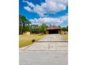 Long driveway leads to a single-story home, with mature landscaping and outdoor features enhancing the property's charm at 7380 Orange Ave, Indian Lake Estates, FL 33855