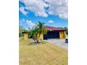 Well-maintained house with a tile roof, mature palms, and a spacious driveway on a sunny day at 7380 Orange Ave, Indian Lake Estates, FL 33855