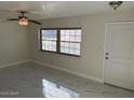 Bright living room with ceiling fan, white walls, new marble floors and large windows at 908 Boulder Dr, South Daytona, FL 32119
