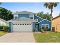 Charming two-story blue home with a manicured lawn, a brick driveway, and a two-car garage at 109 Fern Springs St, Debary, FL 32713