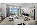 Bright and airy living room featuring a white sofa, stylish decor, and expansive windows overlooking the pool and lake at 165 Azure Mist Way, Daytona Beach, FL 32124
