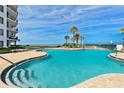 A luxurious pool area with clear blue water, palm trees, and ample seating for relaxation at 2425 S Atlantic Ave # 1202A, Daytona Beach Shores, FL 32118