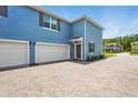 View of home showing the two-car garage, side entry door, and brick-paved driveway at 3049 Meleto Blvd, New Smyrna Beach, FL 32168