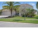 Home featuring a three-car garage, covered entry, well-kept lawn and tropical landscaping at 3229 Medici Blvd, New Smyrna Beach, FL 32168