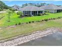 Picture-perfect backyard featuring lush green lawn, meticulous landscaping, a screened lanai, and tranquil lake views at 3322 Modena Way, New Smyrna Beach, FL 32168