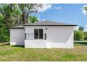 Rear exterior view with sliding glass door to small patio, stucco siding, and green grass at 544 E Voorhis Ave, Deland, FL 32724