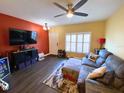 Living room features a ceiling fan, hardwood floors, a large sofa, and a mounted television on a red accent wall at 783 Shropshire Loop, Sanford, FL 32771