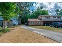 Inviting brick home with a lengthy driveway, surrounded by vibrant greenery beneath a partly cloudy sky at 818 Sugar House Blvd, Port Orange, FL 32129