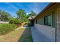 View of the exterior and side yard featuring a brick accent wall and mature landscaping at 834 Sugar House Dr, Port Orange, FL 32129